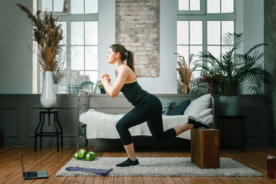 A strong and beautiful sports fitness girl in sportswear lunges with boxes 
