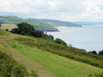 Scenic view of agricultural field by sea against sky