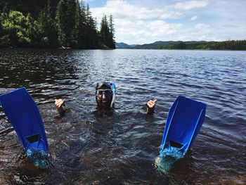 Scuba diver swimming in river while gesturing against sky