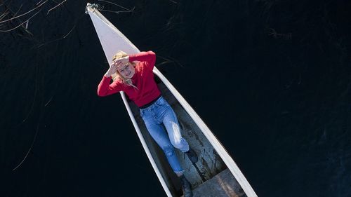 Midsection of woman holding umbrella while standing against water