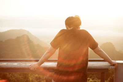 Rear view of shirtless man looking at mountains against sky