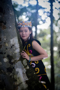 Portrait of young woman standing against window