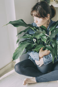 Woman sitting on potted plant at home