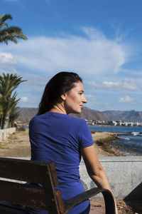 Young woman looking at sea shore against sky