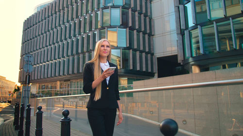 Portrait of young woman standing against buildings