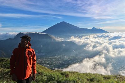 Rear view of woman standing on mountain against sky