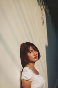 Portrait of young woman against wall