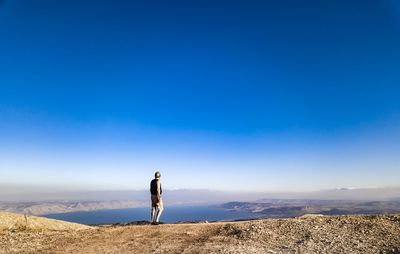 Man standing on mountain against blue sky