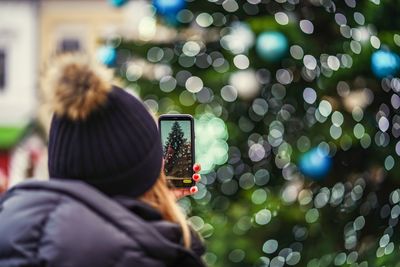 Rear view of person photographing through mobile phone