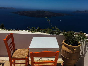 Chairs and table by sea against plants