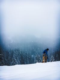 Person walking with sledge on snow covered field in foggy weather