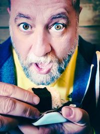 Portrait of shocked man holding food against wall