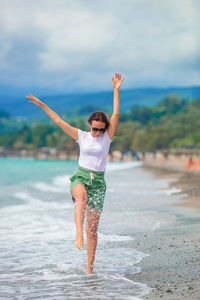 Full length of man with arms raised on beach