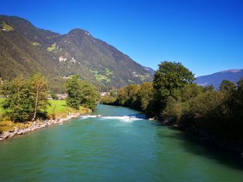 Scenic view of lake and mountains against clear blue sky