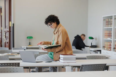 Side view of young woman using laptop at office