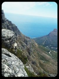 Scenic view of sea by cliff against sky