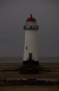 Lighthouse by sea against clear sky