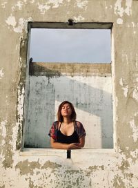 Portrait of young woman against wall