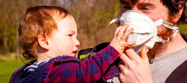 Baby boy trying to remove his fathers face mask 