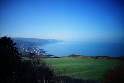 Scenic view of sea and mountains against clear blue sky