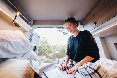 Young woman using laptop in camper