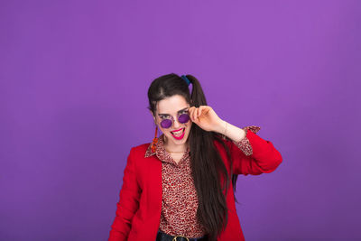 Portrait of young woman standing against blue background