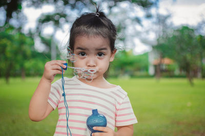 Cute girl blowing bubbles while playing at park