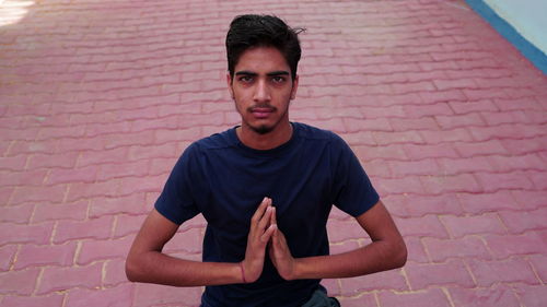 Portrait of young man standing against brick wall