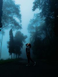 Side view of man photographing in forest