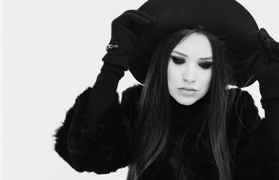 Close-up of young woman wearing hat against white background