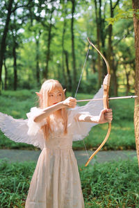 Woman playing with bow and arrow in forest