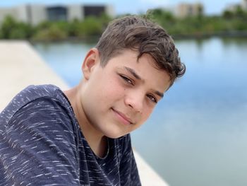 Portrait of teenage boy standing against lake