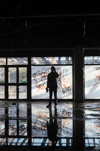 Rear view of silhouette man and woman walking through glass window