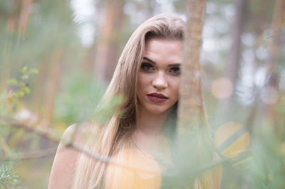 Portrait of young woman against trees