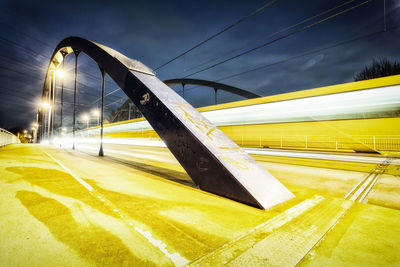 Blurred motion of yellow train on bridge at night