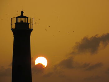 Silhouette lighthouse against sky during sunset