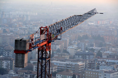 Crane at construction site against buildings in city