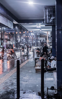 People in illuminated city during rainy season