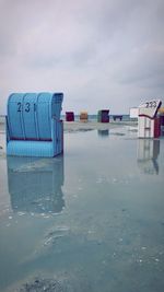 Deck chairs on beach against sky