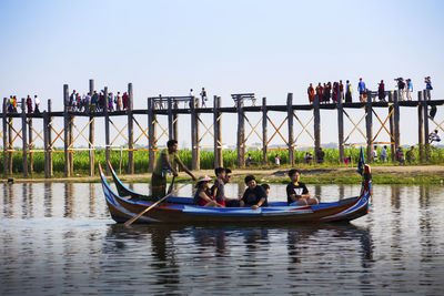 People sitting on boat against clear sky