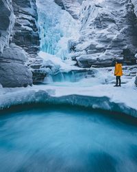 Side view of young man standing by frozen waterfall