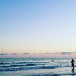 Silhouette man standing on beach against clear sky during sunset