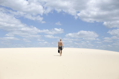 Rear view of man walking on sand