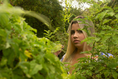 Portrait of young woman against plants