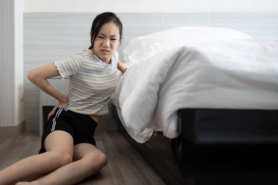 Midsection of woman sitting on bed at home