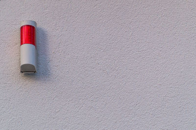 Close-up of red alarm button on white wall