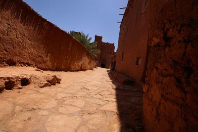 Footpath amidst old buildings against sky