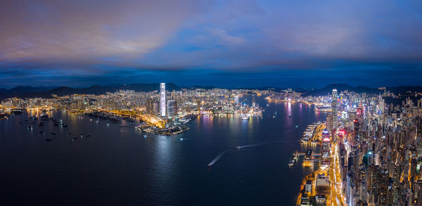 High angle view of illuminated city by sea against sky