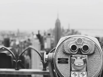 Close-up of coin-operated binoculars against cityscape