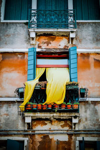 A yellow curtain draped out of a window in venice